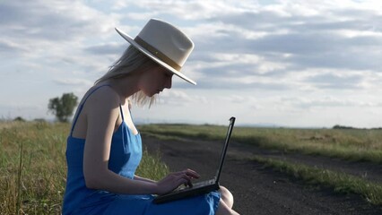 Sticker - Girl in blue dress with laptop computer sit on country road in summer.