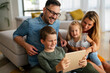© NDABCREATIVITY - Device technology family online education concept. Happy family with digital devices at home.