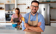 © NDABCREATIVITY - Portrait of handsome happy man cooking at home preparing food in kitchen.