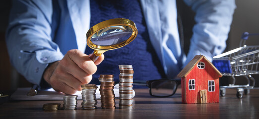 Wall Mural - Real estate agent holding magnifying glass on house model.