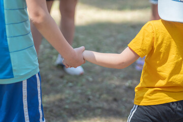 Two kids friends friends hold each other's hands, in yellow and blue T-shirts close-up.