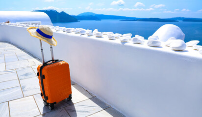 The banner of travel  in summer concept with Orange luggage with hat and landscape view of Oia town in Santorini island in Greece , Greek landscape as blue sky background