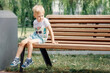 Small child plays in park. Kid is sitting on a park bench.