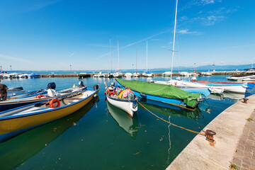 Wall Mural - Small port on the coast of Lake Garda (Lago di Garda). Village of Lazise, tourist resort in Verona province, Veneto, Italy, southern Europe. On the horizon the Lombardy coastline.