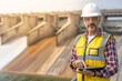 © Attayoot - A dam engineering doing his checking routine. He is wearing a white hard hat and yellow transparent vest. He is standing by the rail by the dam.