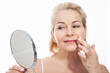 © missty - Happy middle aged woman model touching face skin looking in mirror. Smiling mature older lady enjoying healthy skin care, aging beauty, skincare treatment cosmetic products concept.
