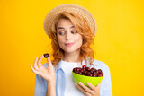 Young woman eats sweet cherries. Portrait of a beautiful girl with cherry on yellow background. Summer fruit picking season. Natural vitamins.