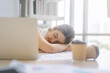© dodotone - Young adult business asian woman fatique and sleep on table at office