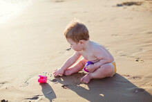 Baby Boy Sitting On Beach Sea