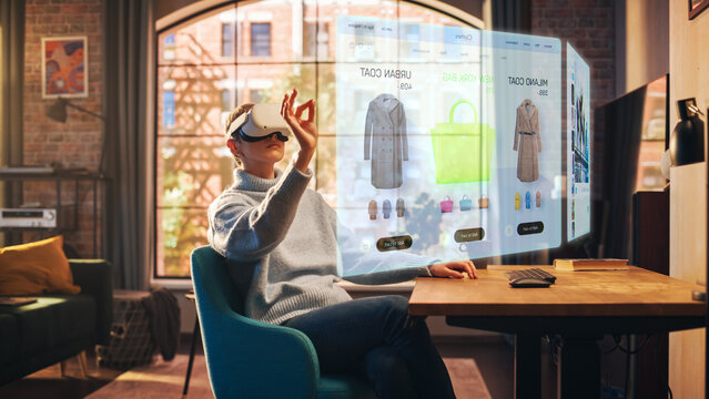 Fototapete - Young Beatiful Women is Using Virtual Reality Headset for Doing an Online Shopping In Stylish Loft Apartment. Casualy Dressed Female is Using Innovative Softwear to Purchase Cloth. 3D Website Concept.