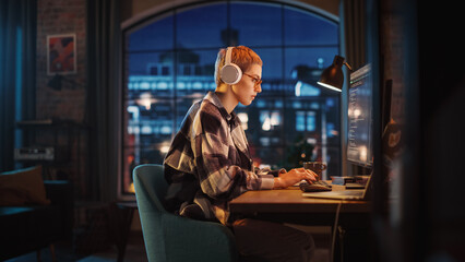 Aufkleber - Young Woman Writing Code on Desktop Computer in Stylish Loft Apartment in the Evening. Creative Female Wearing Headphones, Working from Home on Software Development. Urban City View from Big Window.