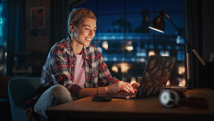 Fototapete - Young Attractive Woman Using Laptop Computer in Stylish Loft Apartment in the Evening. Creative Female Smiling, Checking Social Media, Browsing Internet. Urban City View from Big Window.