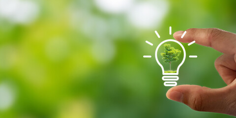 hand holding light bulb icon on green background. demonstrates energy savings and turns to solar and
