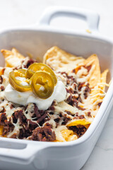 Wall Mural - nachos with beef minced meat and cheese served with whipped cream and jalapenos