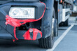 Broken truck bumber fixed-up with a red duct-tape. Delivery truck with a cracked front plastic bumper
