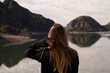 Portrait of a young woman in her 20s, contemplating the natural landscape. View of the mountains and sky reflection in the lake water, in the background.  