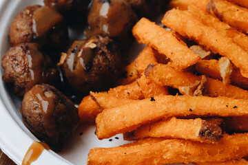 Spicy meatballs with sweet potato fries on white plate