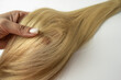 © Irina - A woman holding a blonde hair ply in her hand