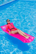 © Дмитрий Ткачук - Happy young woman in sunglasses and pink bikini floating on inflatable mattress by the pool. Summer vacation concept. Travel by sea