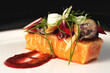salmon with vegetables on top and red sauce on white plate