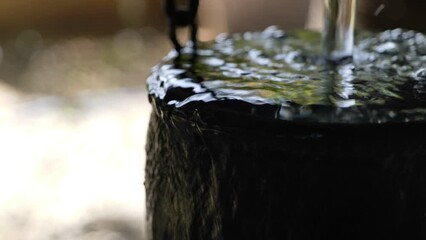 selective focus at water overflow from clay pot or hanging bowl. decorative spillway fountain bowl w