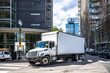 © vit - Big rig day cab white semi truck with long box trailer making local commercial delivery at urban city with multilevel residential apartments buildings turning on the city street with crossroad