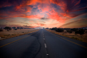 Beautiful South African road that runs through the middle of the African savannah under the typical African sun, which is characterized by beautiful colors at sunset.