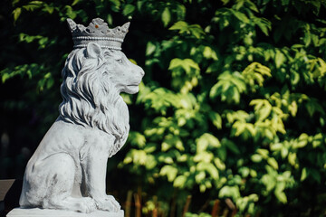 Large plaster sculpture of a lion isolated from green leaf background.