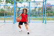 © JENOCHE - girl with afro hairstyle with a ball on a basketball court