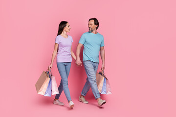 Sticker - Full length portrait of lovely people hold arms walking hold packages isolated on pink color background