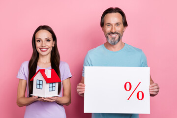 Poster - Portrait of two cheerful partners hold little house empty space poster isolated on pink color background