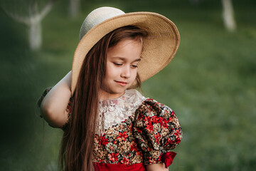 Wall Mural - Beautiful girl in a vintage dress 7-8 years old posing in the garden. Beautiful spring garden. The concept of a happy childhood, peace and happiness.