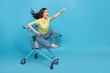 Full length photo of cool millennial brunette lady go in trolley yell wear t-shirt jeans footwear isolated on blue background