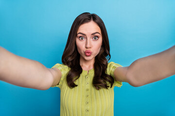 Poster - Photo of cute millennial brunette curly hairdo do selfie blow kiss wear green top isolated on blue color background