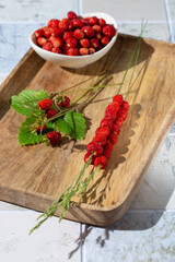 Wall Mural - Wild strawberry berries with leaves on wooden tray. Summer still life with wild strawberries.