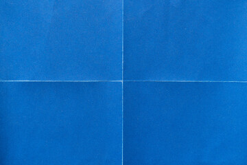 Wall Mural - Blue paper background with creases that separates paper into four parts