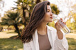 © Look! - Relaxed young caucasian girl with bottle of purified water eliminates thirst in street. Brunette with long hair wears shirt. Lifestyle concept