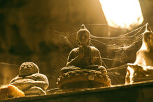 Closeup Of Stone Buddha Statues Covered In Spider Web In A Cave.