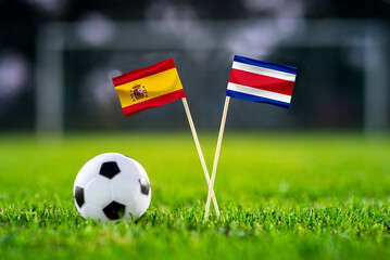 Wall Mural - October 2022: Spain vs Costa Rica, Al Thumama Stadium, Football match wallpaper, Handmade national flags and soccer ball on green grass. Football stadium in background. Black edit space.