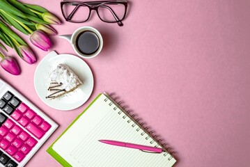 Flat lay view of desktop surface, tulips, coffee with cake and notepad with calculator on pink light background with copy space, holiday in financial sphere