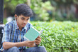 © SBM Creatives - Indian boy reading a book and listening to audiobook from headset