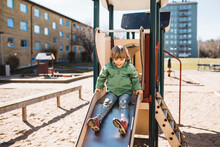 Boy Sitting On Top Of Slide