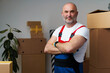© fotofabrika - Portrait of a middle-aged man mover in uniform standing against stacked boxes