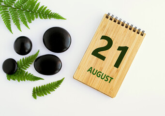 August 21. 21th day of the month, calendar date. Notepad, black SPA stones, green leaves. Summer month, day of the year concep