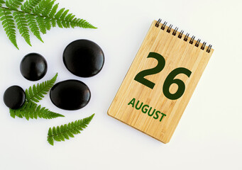 August 26. 26th day of the month, calendar date. Notepad, black SPA stones, green leaves. Summer month, day of the year concep
