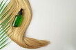 A natural oil or serum for hair care lying on a ply of blonde hair