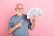Photo of pretty positive guy pensioner dressed grey pullover glasses pointing money fan isolated pink color background