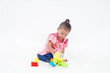 © Akmalism Photography - Lovely little cute asian girl playing on the floor with lots of colorful plastic blocks in studio, isolated on white background