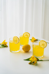 Wall Mural - fresh citrus tonic near lemons and yellow alstroemeria flowers on white background.