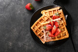 Fototapeta  - Belgium waffles. Homemade waffles with strawberries, powdered sugar and cup of coffee on black plate on black stone table background. Breakfast. Top view. Mockup for design idea.